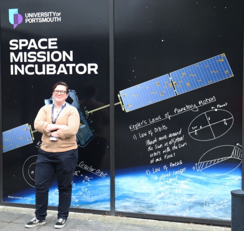 Dr Lucinda King standing in front of the sign for the Space Mission Incubator service