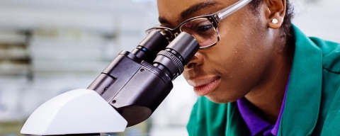 Medical biotechnology student using microscope in lab