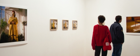 Two people looking at photographs on wall at exhibition