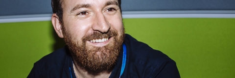 bearded man wearing a dark blue shirt and smiling