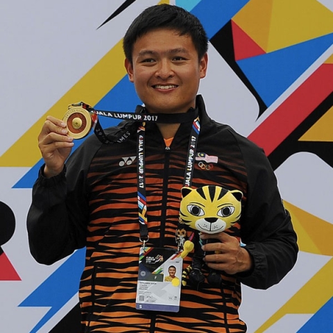 Benjamin Khor holding up medal and stuffed animal smiling to camera after winning gold at 2017 Southeast Asian Games