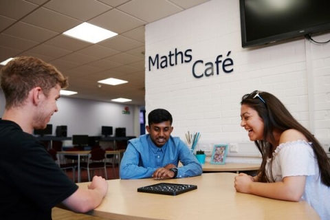 Students sat around table in the Maths Cafe playing a game
