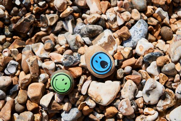 Pebbles on the beach two of them have smiley face stickers on them