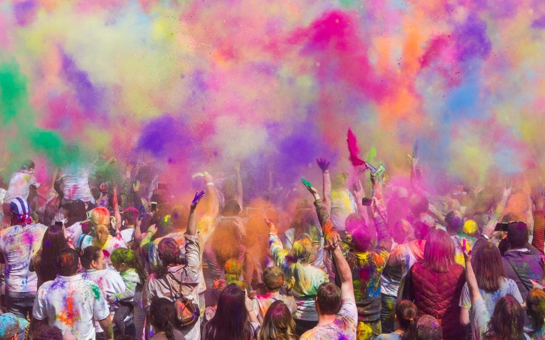 a crowd of people throwing coloured powder paint