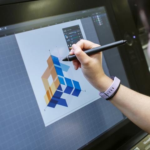 A student drawing a geometric design on a Wacom tablet screen