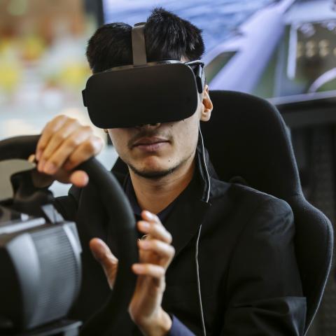 Male research participant driving car in VR headset
