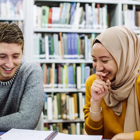 Students in the library studying, smiling and laughing