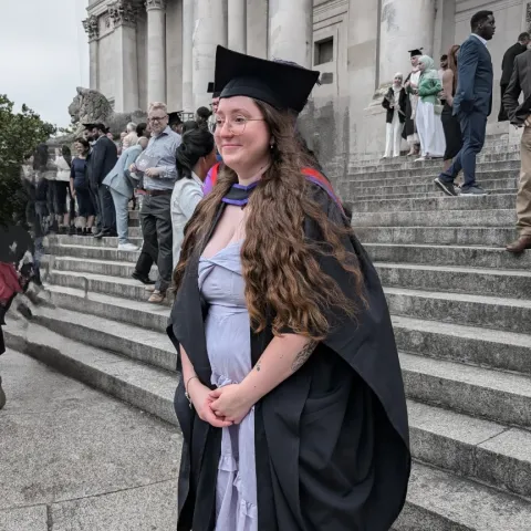 Student wearing graduation cap and gown.