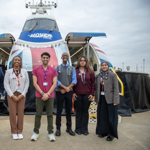 Medical degree students stand in front of the Hovertravel hovercraft smiling