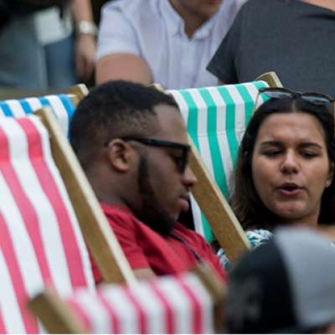 two students sat on deckchairs outside 