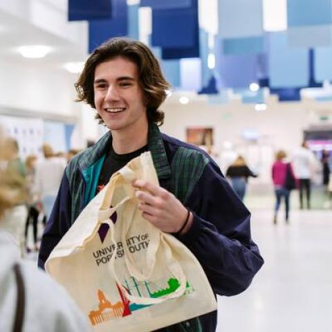 A student at an Open Day holding a University of Portsmouth tote bag