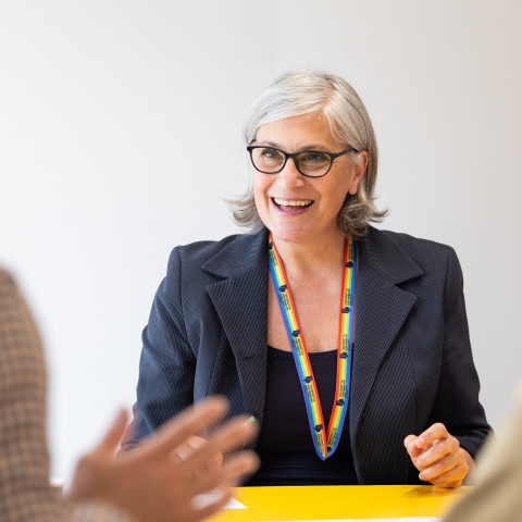 A person smiling whilst in conversation with another.