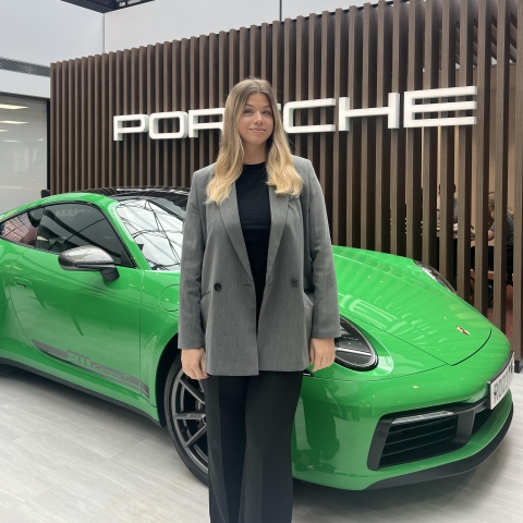 Daisy stands in front of a green Porsche 911