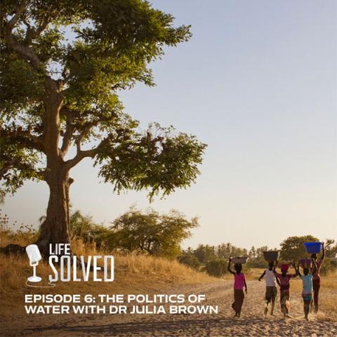 Children and women walking carrying water buckets on their heads across a sandy path. Life Solved logo and title and bottom.