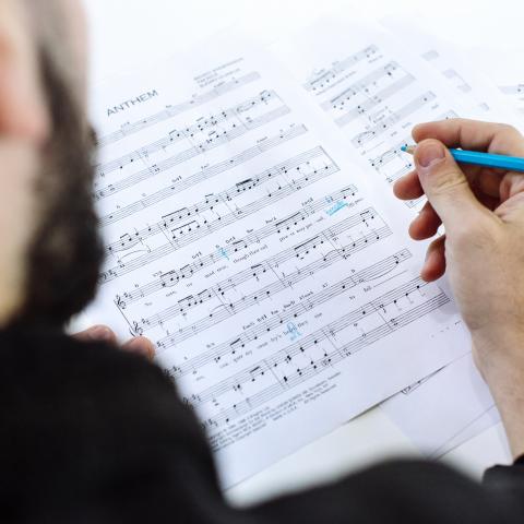 Person marking sheet music with light blue pencil