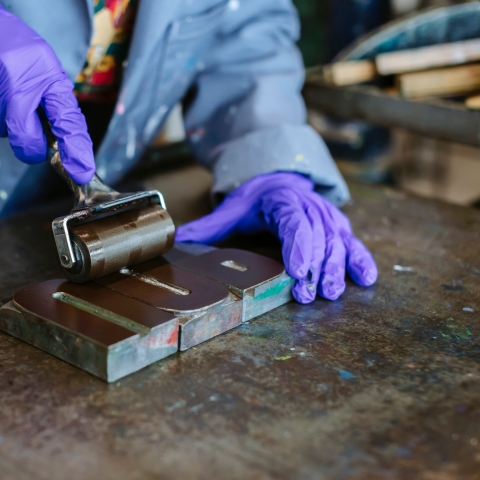 A person with gloves using a letterpress