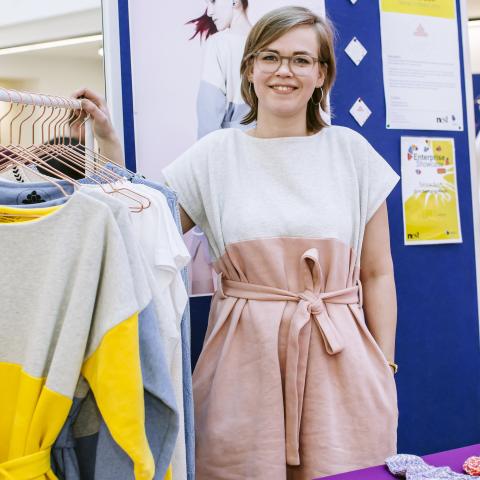 Female University of Portsmouth design student standing by clothing rail