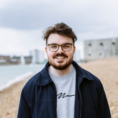 Male student in glasses with beard walking along the stone beach at Old Portsmouth