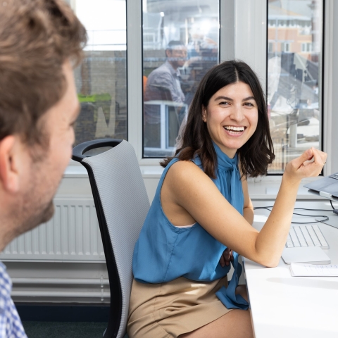 Woman in office environment smiling with colleague