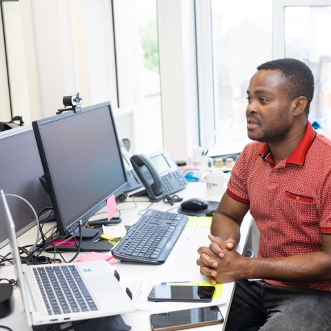A man sat at a desk in front of a computer monitor.