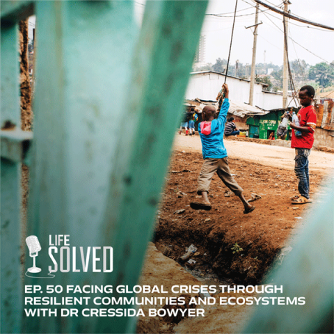 Children playing and swinging from cable by a gate in Nairobi slum. Life Solved logo and title