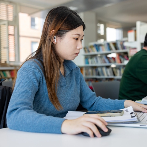 Female student with long hair in the library on a computer