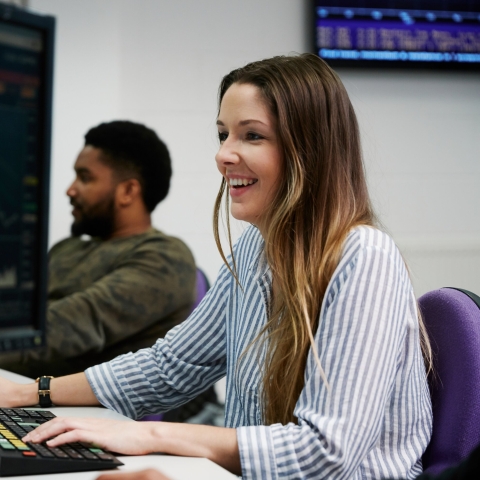Woman smiling at computer using financial technology.
