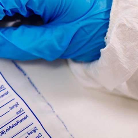 Forensic information technology student labelling an evidence bag wearing gloves