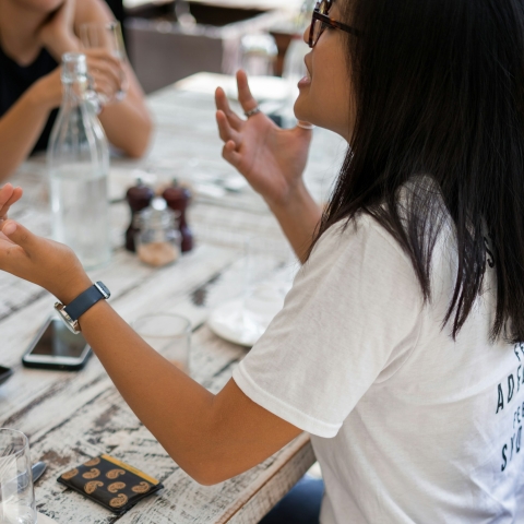 A person sat at a table talking and gesticulating