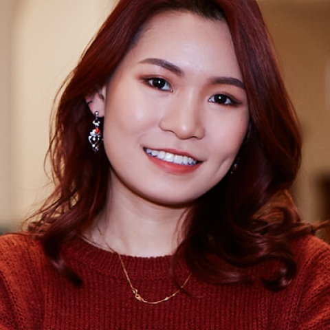A woman with red hair and top, smiling