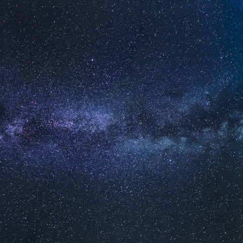 An image of a galaxy - a dark blue sky dotted with stars and a white cloudy patch across the middle