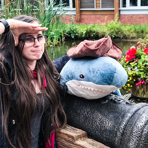 Sarah Ryan standing with a salute with a plushie of a shark