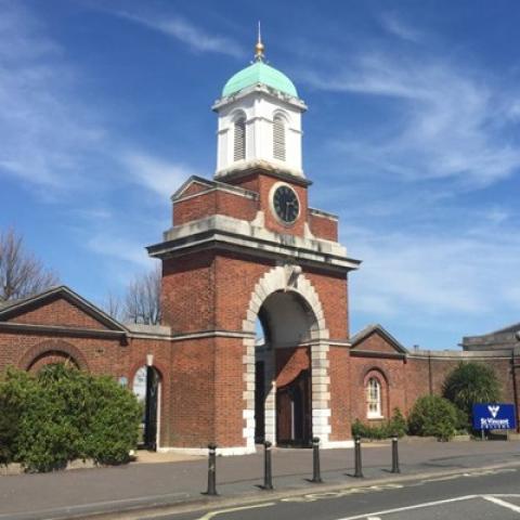 Historic, red-brick walls and archway with a clock tower at the entrance to St Vincent College in Gosport