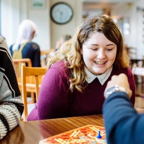 Group of students play snakes and ladders in a cafe