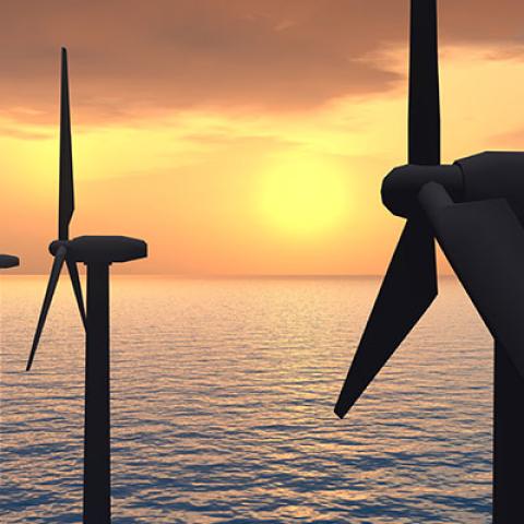 A row of wind turbines in the sea, in front of a sunset