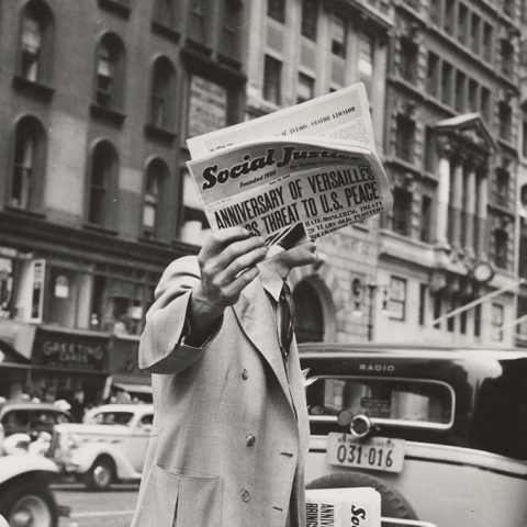Old black and white image of a man holding a newspaper on a New York street