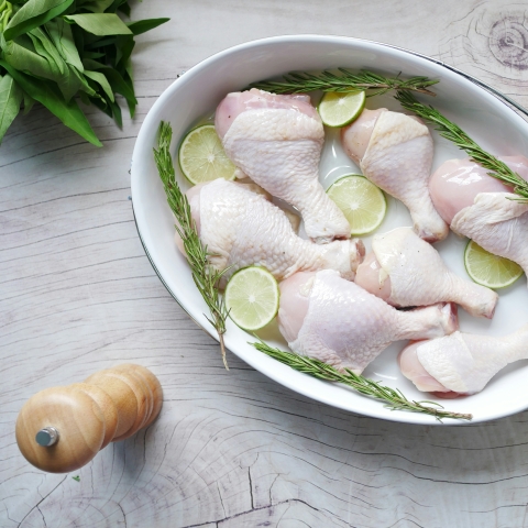 Raw chicken drumstick on in bowl on table