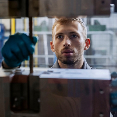 Student in overalls aligning drill head of machinery at Technology Facilities