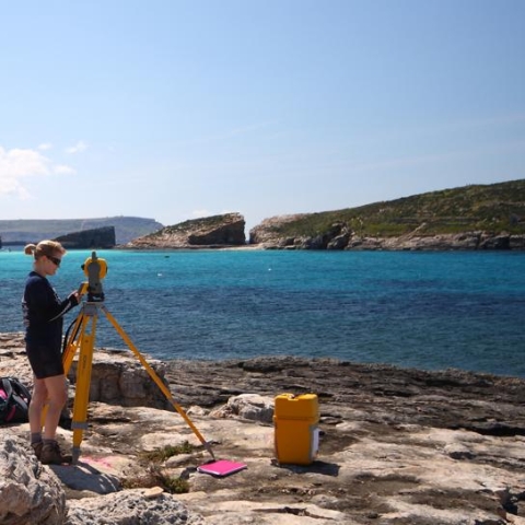 Researcher using a theodolite on the coast in Malta
