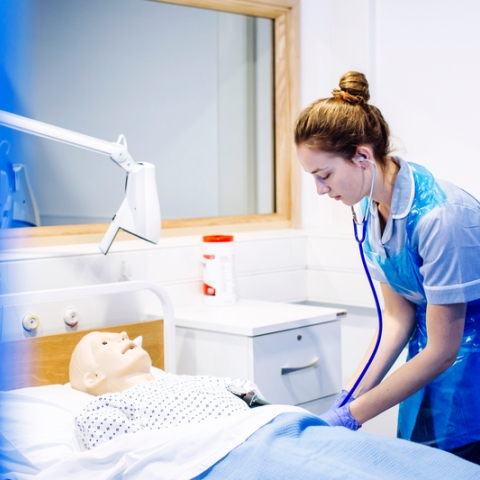 Female nursing student practising work with mock patient