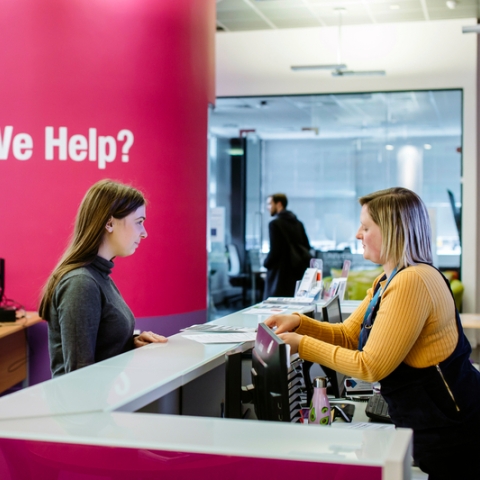 Female student standing at careers and employability help desk
