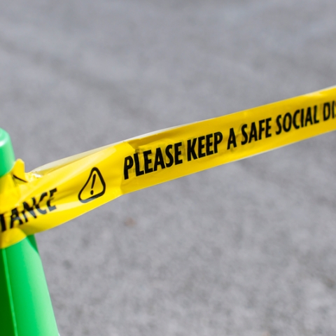 a green cone with tape warning of social distance