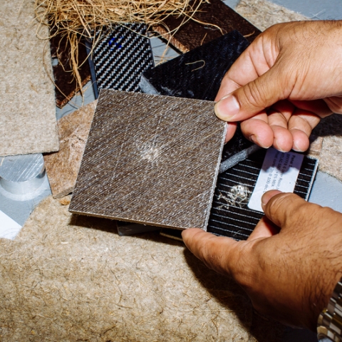 male hands hold small solid square panel which is made from materials including plant waste