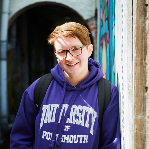 Student in purple hoodie standing in back alleys