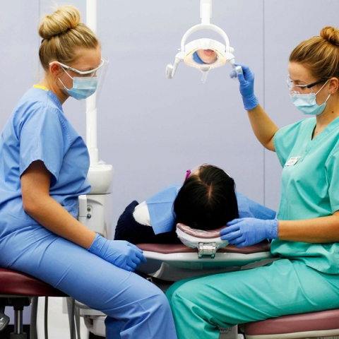 Dental academy students examine patient