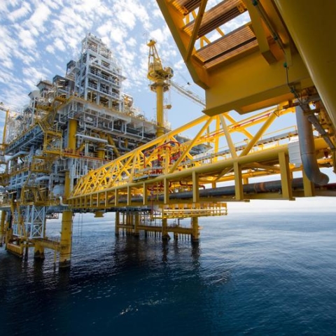 An oil rig in an ocean against a blue sky