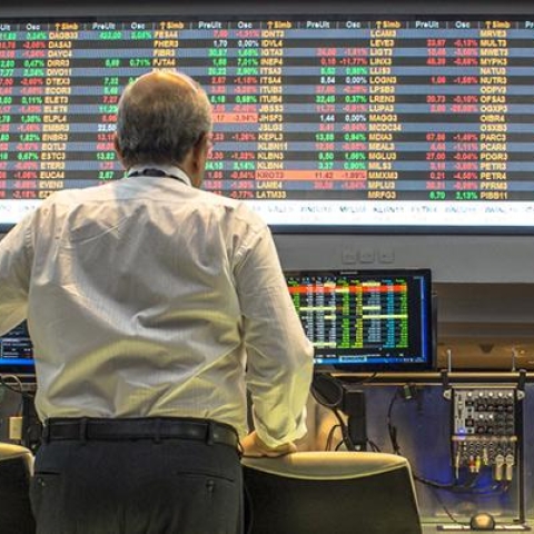 Person standing in front of screens showing financial data