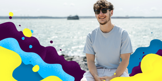 Male student sat at the beach 