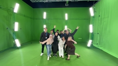 A group of people posing in front of a green screen.