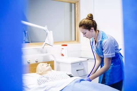 Female nursing student practising work with mock patient